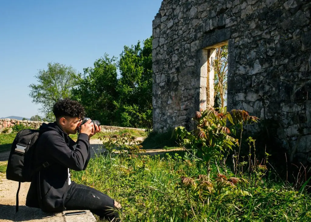 мъж снима руини от каменни сгради